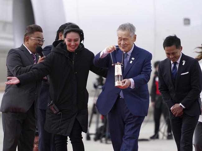 Tokyo 2020 Olympics officials excitedly receive the Olympic flame in Tokyo. The IOC may be about to blow it out. Picture: AP