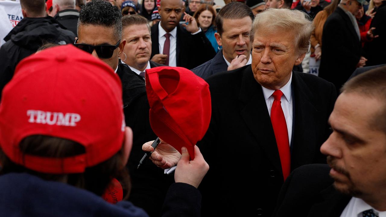 Republican presidential candidate Donald Trump autographs hats while visiting with supporters outside the polling site at Londonderry High School on January 23, 2024. (Photo by CHIP SOMODEVILLA / GETTY IMAGES NORTH AMERICA / Getty Images via AFP)
