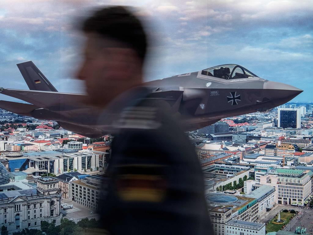 An unidentified participant walks past a poster advertising the F-35 stealth multirole fighter over a Berlin skyline. This stealth fighter is being sold to various nations including Turkey. Picture: AFP