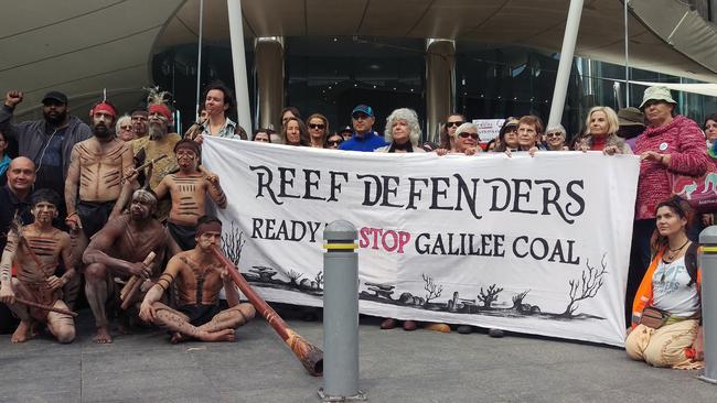 Anti-mining protesters pose for a photograph outside mining giant Adani's offices during a rally in Brisbane, Thursday, July 16, 2015. The group delivered a large collection of individually-written pledges by opponents to the planned development of Queensland's Galilee Basin, who have vowed to stand up against the proposals. (AAP Image/Jamie McKinnell) NO ARCHIVING