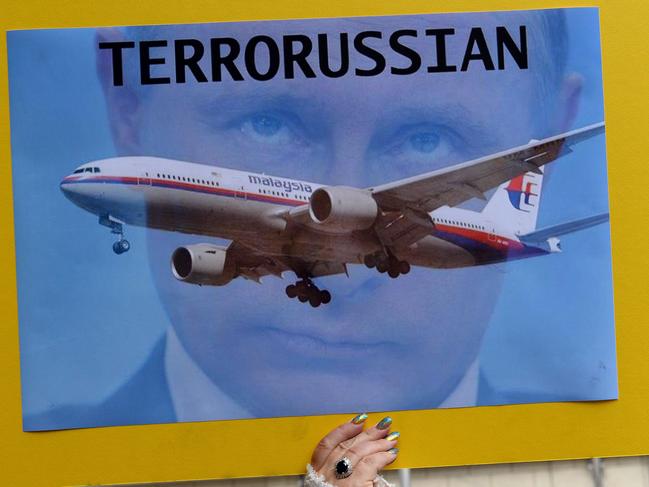 A member of the Australian Ukrainian community raises a placard carrying picture of the Russian President Vladimir Putin during a protest rally in Sydney on July 19, 2014. Demonstrators demanded not to let Putin come to Australia for G20 leaders summit in November 2014. Flags flew at half-mast to honour the Australians killed in the Malaysia Airlines crash over Ukraine as Foreign Minister Julie Bishop said it was 