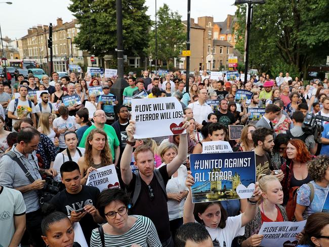 People hold up signs saying 'united against terror' as they attend a vigil outside Finsbury Park Mosque. Picture: Dan Kitwood/Getty Images