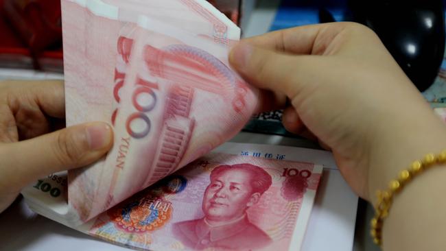 A teller counts yuan banknotes in a bank in Lianyungang, east China's Jiangsu province on August 11, 2015. China's central bank on August 11 devalued its yuan currency by nearly two percent against the US dollar, as authorities seek to push market reforms and bolster the world's second-largest economy. CHINA OUT AFP PHOTO