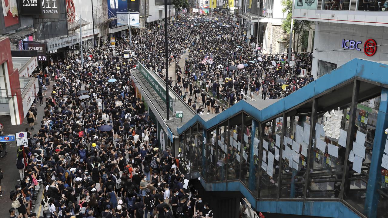 A sea of black-shirted protesters, some with bright yellow helmets and masks but many with just backpacks, marched down a major street in central Hong Kong yesterday.