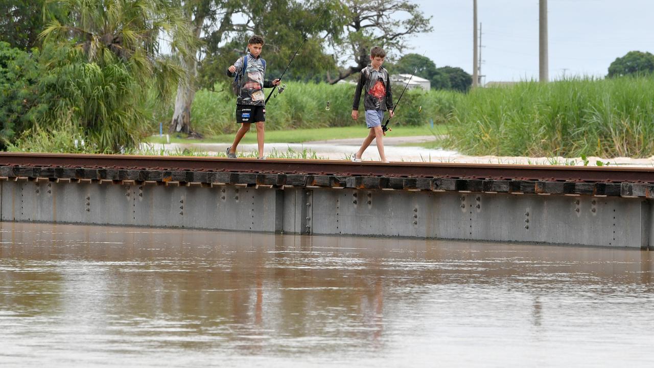 Sunday February 9. Flooding at Plantation Creek in Ayr cuts the Bruce Highway to all traffic apart from trucks. Boys walk the nearby rail bridge. Picture: Evan Morgan