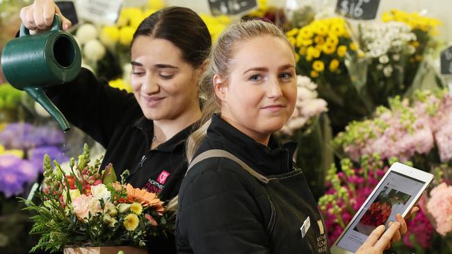 Stephanie Celere, 20, and Jaslyn Anderston, 22, process online orders for flowers at Northside Flower Market, Stafford. Picture: Liam Kidston.