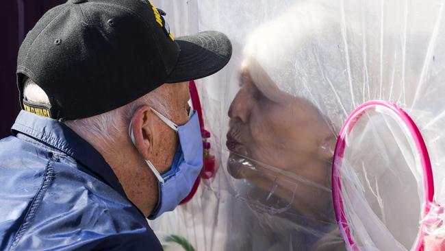 Betty Van Putten, right, moves in to kiss her husband, Stan Van Putten, through a hug tent at the Crossroads Senior Living community in Lakewood, Colorado. Picture: AFP