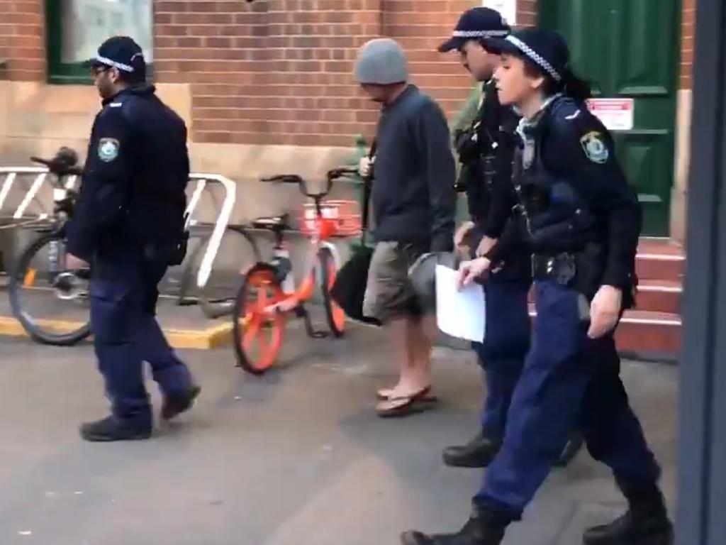 A man is led away by police after attempting to run from the XPT at Sydney's Central Station after the last train arrived from Melbourne as the NSW-Victoria border is locked down. Picture: Sydney Pead