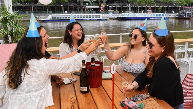 People clink glasses for a drink at a cafe on Melbourne's Yarra River.