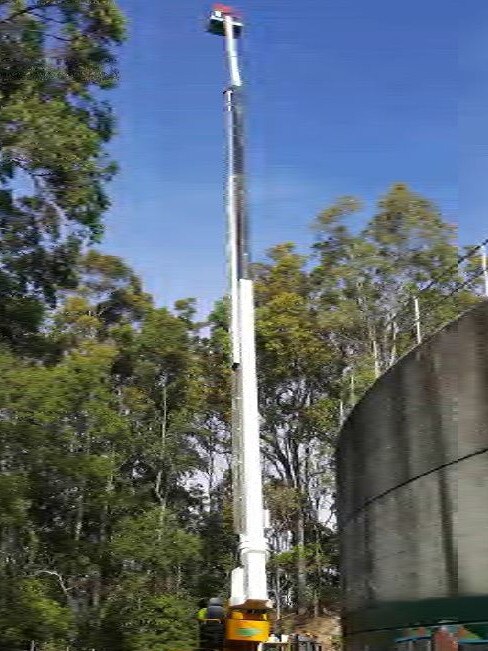 A cherry picker shows the height of a planned telecommunications tower in the Currumbin Valley on the Gold Coast.