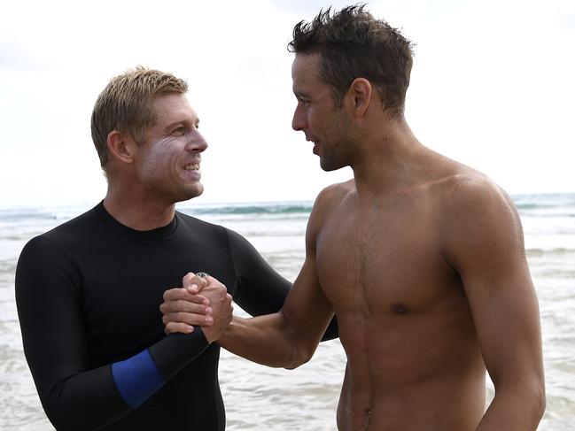 Australian surfer Mick Fanning shakes hands with South African swimmer Chad le Clos (right) after hosting a surf lesson during the XXI Commonwealth Games at Kirra Beach on the Gold Coast, Australia, Wednesday, April 11, 2018. (AAP Image/Tracey Nearmy) NO ARCHIVING