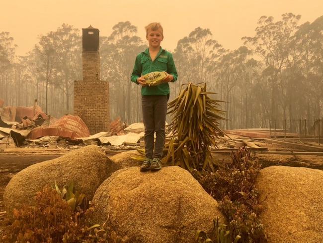 Harper Ireland with the destroyed family property behind him. Picture: Supplied