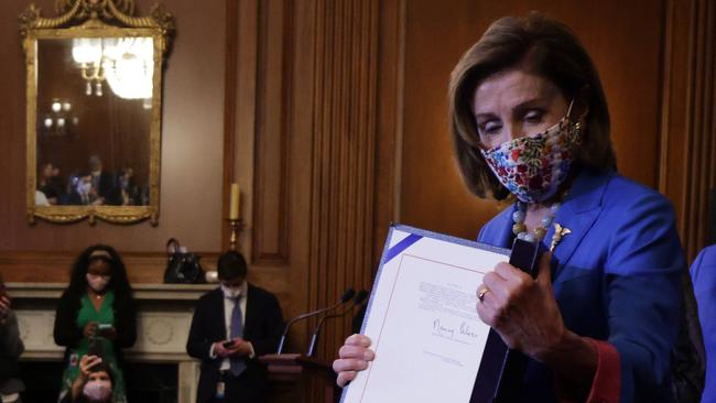 Nancy Pelosi parades the bill sent to Joe Biden on Friday. Picture: AFP