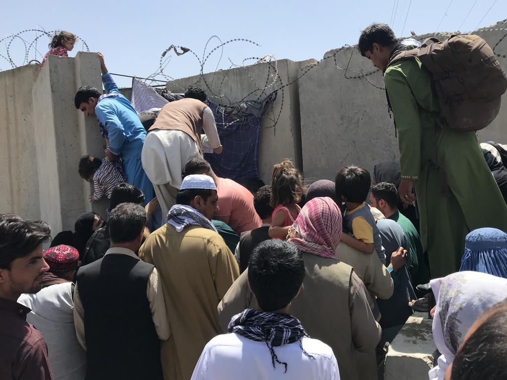 Families struggle to scale the boundary wall to the international airport. Picture: STR/NurPhoto via Getty Images