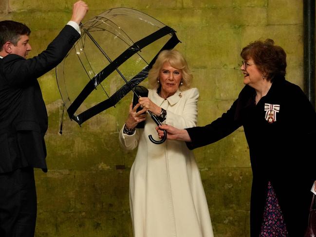 Queen Camilla hands her umbrella to an aide as she arrives for a Musical Evening at Salisbury Cathedral, in Salisbury, England. Picture: AFP