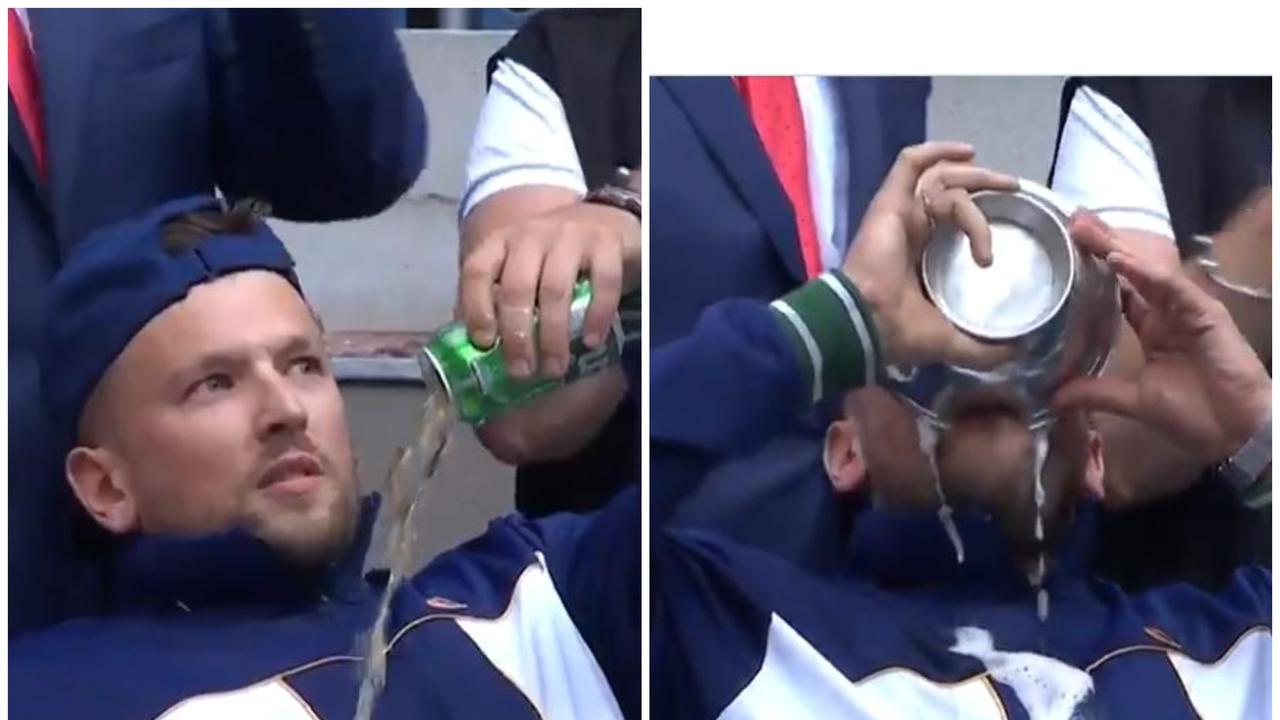 Dylan Alcott sculls a beer from his trophy.