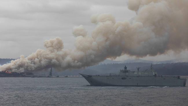 HMAS Adelaide arrives in Eden where the town’s timber mill is ablaze. Picture: Sean Davey