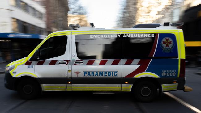 MELBOURNE, AUSTRALIA - JULY 21: An ambulance drives through the CBD on July 21, 2022 in Melbourne, Australia. Victoria recorded 14,312 official cases of COVID-19 in the last 24-hour reporting period, with 875 people hospitalised with the virus, including 46 in intensive care. 37 deaths were also included in this reporting period. While the Federal government has not implemented any COVID-19 restrictions in response to the latest COVID-19 wave, concerns over rising cases of the Omicron subvariants across Australia have seen health authorities recommend the use of face masks indoors, and for people to work from home where possible. (Photo by Asanka Ratnayake/Getty Images)