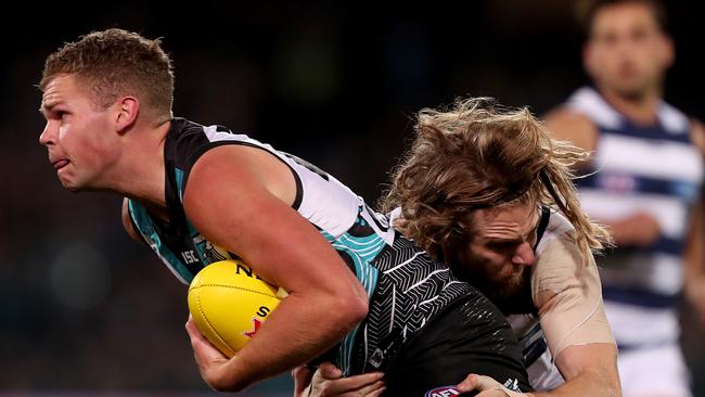 Dan Houston of the Power is tackled by Cameron Guthrie of the Cats at Adelaide Oval on Saturday. Picture: James Elsby/Getty Images