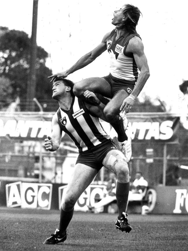 Warwick Capper flies over North Melbourne’s Mick Martyn in 1991.
