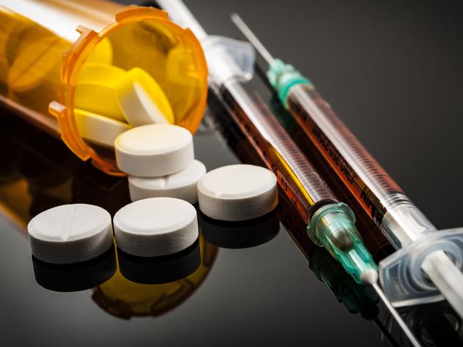 Opioid epidemic, drug abuse concept with closeup on two heroin syringes or other narcotics surrounded by scattered prescription opioids. Oxycodone is the generic name for a range of opioid painkillers