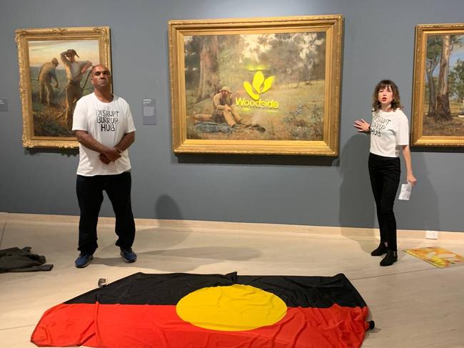 Artist Joana Partyka and Ballardong Noongar man Desmond Blurton protesting against Woodside’s Burrup Hub by spraypainting the company’s logo on the famous piece in the Art Gallery of WA last year.