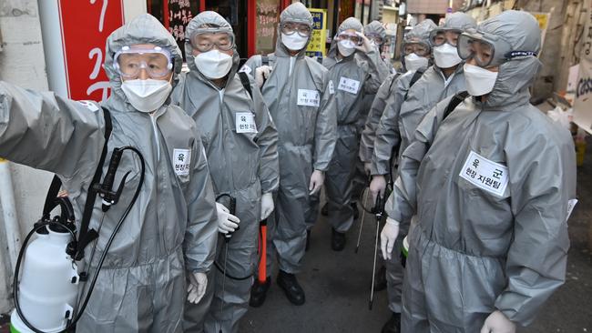 South Korean soldiers have been seen wearing protective gear prepare to spray disinfectant on the streets to help prevent the spread of coronavirus. Picture: Jung Yeon-je/AFP