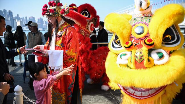 A man dressed as the Chinese God of Wealth distributes Fai Chun traditional decoration for good luck and prosperity at a Lunar New Year event in Hong Kong on January 10. Picture: Peter Parks / AFP.