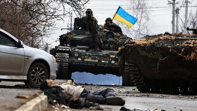 A Ukrainian tank patrols on Saturday the body-strewn streets of Bucha. Picture: Reuters