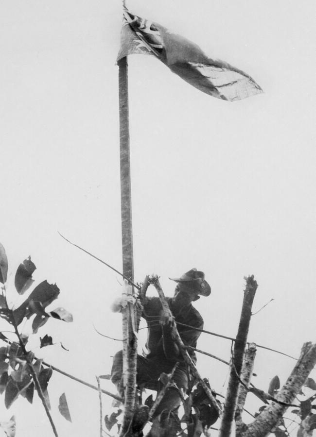 Sgt Tom Derrick (DCM) of Adelaide, SA, raises the flag after a successful attack against the Japanese-held village of Sattelberg on November 24, 1943. Picture: Courtesy Australian War Memorial 016246