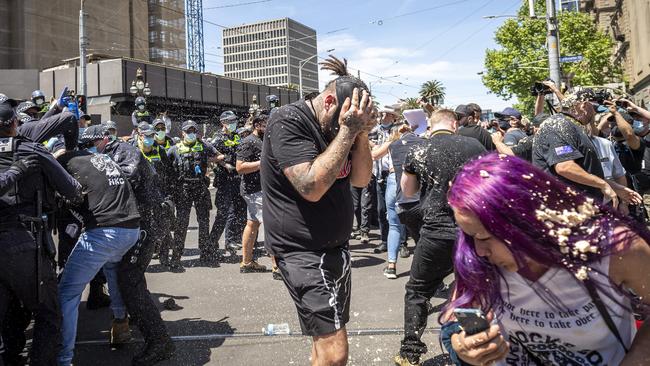 A protester covers his face after being pepper sprayed. Picture: Jake Nowakowski