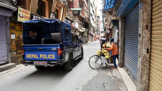 Police remove a fruit vendor from the street as Nepal locks down its streets. Picture: Brad Fleet