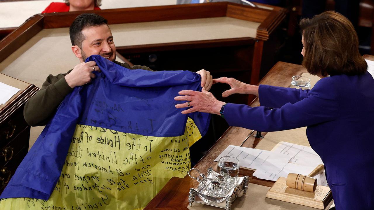 Volodymyr Zelenskyy presents the Ukrainian flag signed by members of the Ukrainian military to US Speaker of the House Nancy Pelosi. Picture: AFP