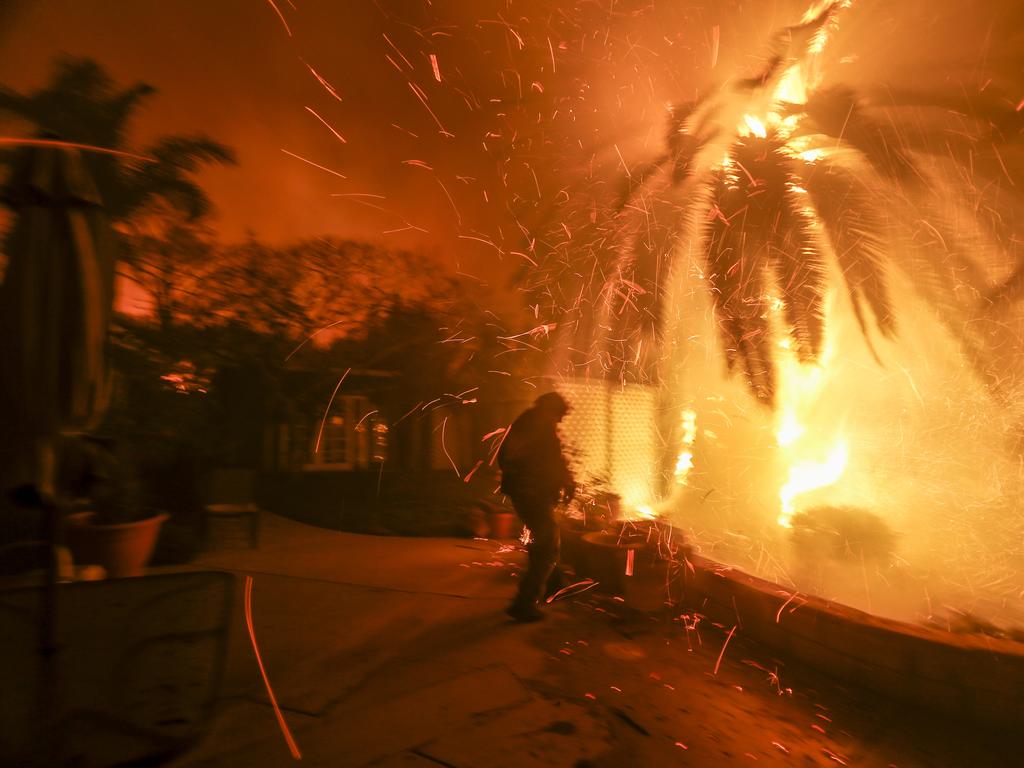 Tim Billow, 62, tries to save his plantings in his backyard as the Woolsey Fire burns in Malibu. Picture: AP