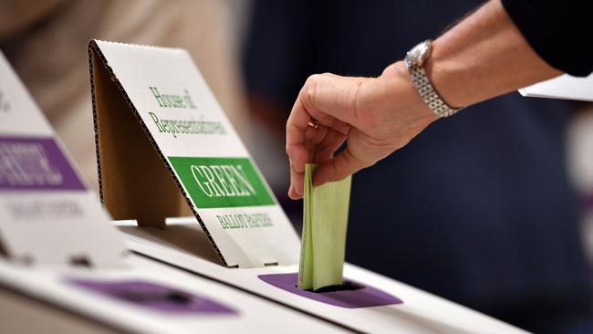 A voters drops her ballot paper into the ballot box. (Photo by Saeed KHAN / AFP)