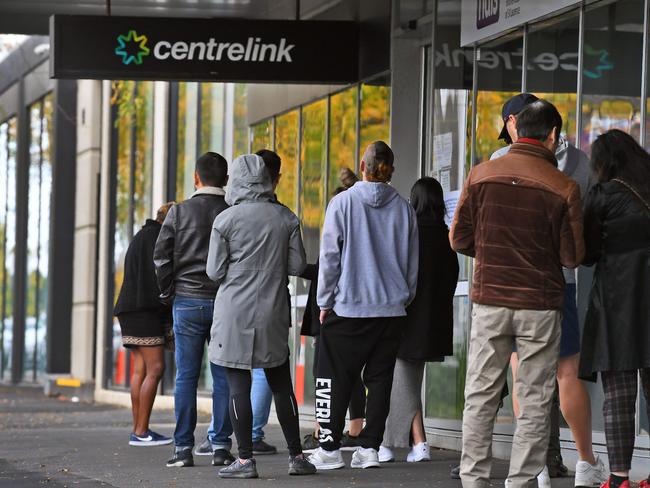 People queue up outside a Centrelink office in Melbourne on April 20, 2020, which delivers a range of government payments and services for retirees, the unemployed, families, carers and parents amongst others. - A report from the Grattan Institute predicts between 14 and 26 per cent of Australian workers could be out of work as a direct result of the coronavirus shutdown, and the crisis will have an enduring impact on jobs and the economy for years to come. (Photo by William WEST / AFP)