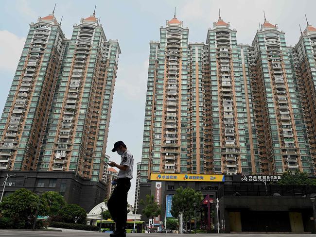 (FILES) In this file photo taken on September 17, 2021, a man walks past a housing complex by Chinese property developer Evergrande in Guangzhou, China's southern Guangdong province. - Embattled Chinese housing giant Evergrande said on September 22, 2021 it had agreed a deal with domestic bondholders that should allow the conglomerate to avoid default on one of its interest payments. (Photo by Noel Celis / AFP)