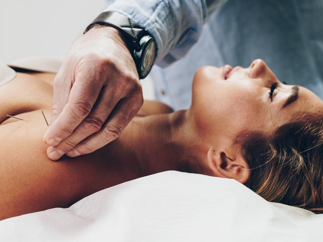 Beautiful young adult woman receiving professional acupuncture and massage treatment.