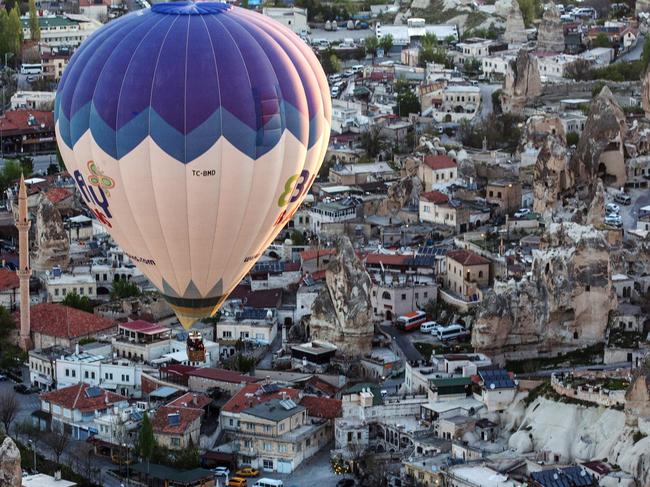 NEVSEHIR, TURKEY - APRIL 17: Tourists take in the view over the town of Goreme during a hot air balloon ride on April 17, 2016 in Nevsehir, Turkey. Cappadocia, a historical region in Central Anatolia dating back to 3000 B.C is one of the most famous tourist sites in Turkey. Listed as a World Heritage Site in 1985, and known for its unique volcanic landscape, fairy chimneys, large network of underground dwellings and some of the best hot air ballooning in the world, Cappadocia is preparing for peak tourist season to begin in the first week of May. Despite Turkey's tourism downturn, due to the recent terrorist attacks, internal instability and tension with Russia, local vendors expect tourist numbers to be stable mainly due to the unique activities on offer and unlike other tourist areas in Turkey such as Antalya, which is popular with Russian tourists, Cappadocia caters to the huge Asian tourist market. (Photo by Chris McGrath/Getty Images)