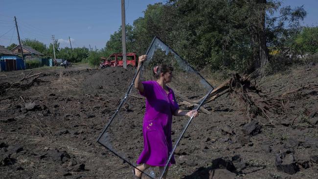 A Ukrainian woman carries a broken window frame, some hours after a rocket landed in front her house in the outskirts of Bakhmut, Eastern Ukraine. Picture: AFP