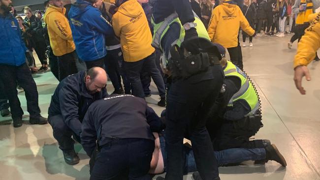 Police and security detain a man on the ground at the MCG on Friday night.