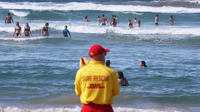 A Surf Life Saving Queensland lifesaver watches over swimmers at Burleigh after a spate of shark sightings and close encounters. Picture: Jason O'Brien