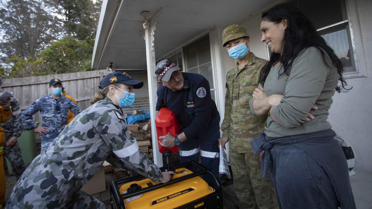 CFA volunteer Shayne O'Dwyer and Australian Defence Force personnel delivery a generator to Sassafras resident Julie Maiden. Picture: Arsineh Houspian