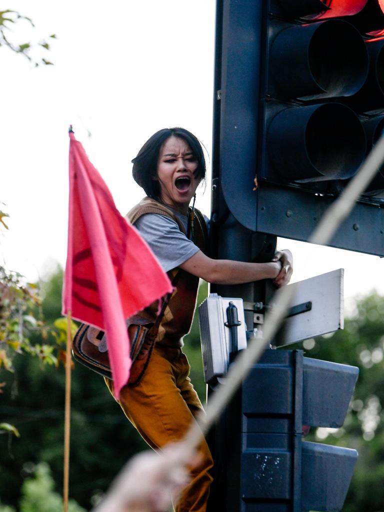 A woman climbs a traffic light pole. Picture: AAP / Morgan Sette
