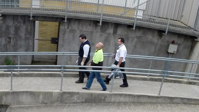 Patrick Perkins (centre) escorted across the watch house compound at the time of his arrest. Picture: News Corp