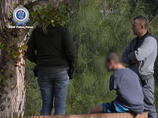 The man sits with his hands cuffed beneath his t shirt as police search his home. Picture: NSW Police.