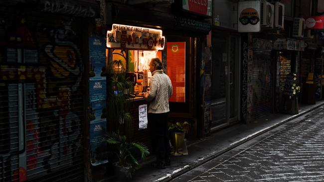 A man orders from a cafe in a small deserted laneway usually packed with open cafes and people during their lunchtime in Melbourne. Picture: AFP