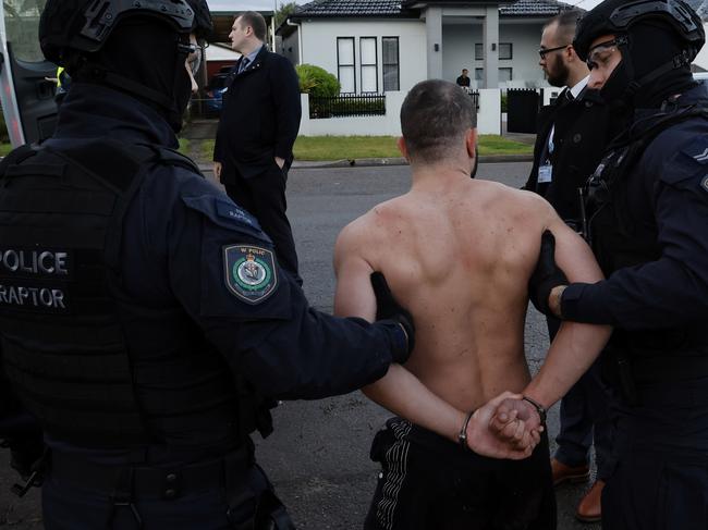 One of the men arrested is taken away by police on Tuesday.