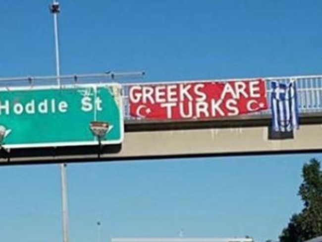 A phallic symbol painted on a Greek flag that hangs over one of Melbourne’s busiest freeways.