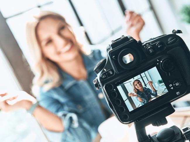 Beautiful young woman in casual wear smiling while recording video